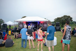 Crowd standing in front of music stage, listening to music