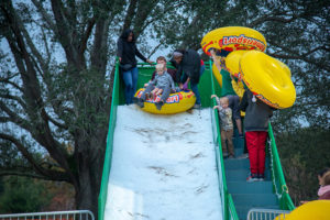 Families sledding down snow slide at winter fest