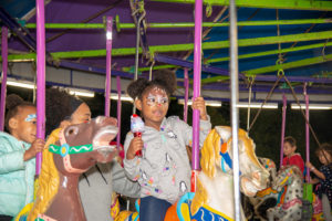 Little girl in facepaint, riding a carousel